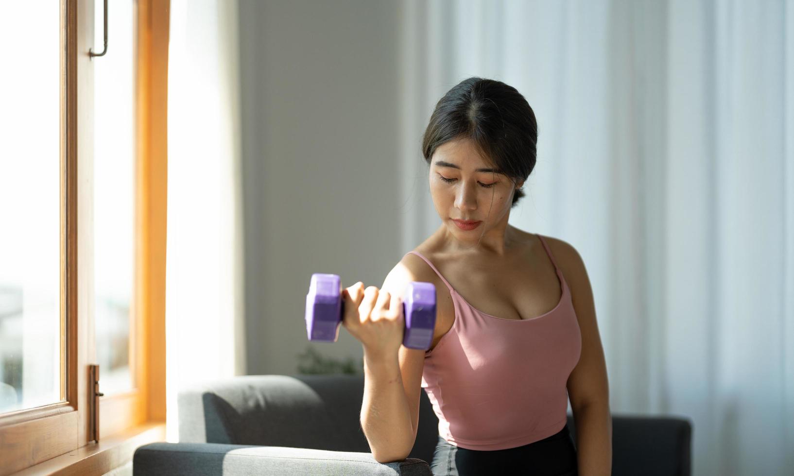 retrato de una joven asiática levantando pesas en casa foto