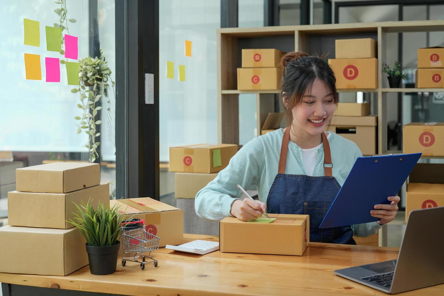 Asian business owner working, checking order to confirm before sending to customer. Female entrepreneur packaging box for delivery. photo