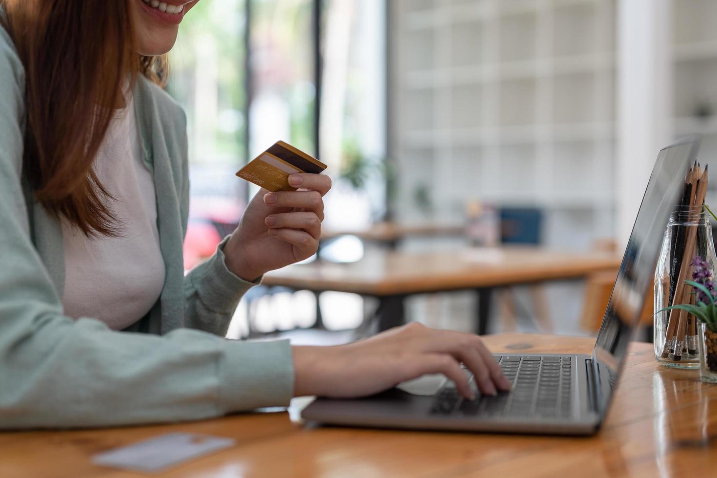 Happy young asian woman resting and browsing internet with laptop holding credit card online shopping concept photo