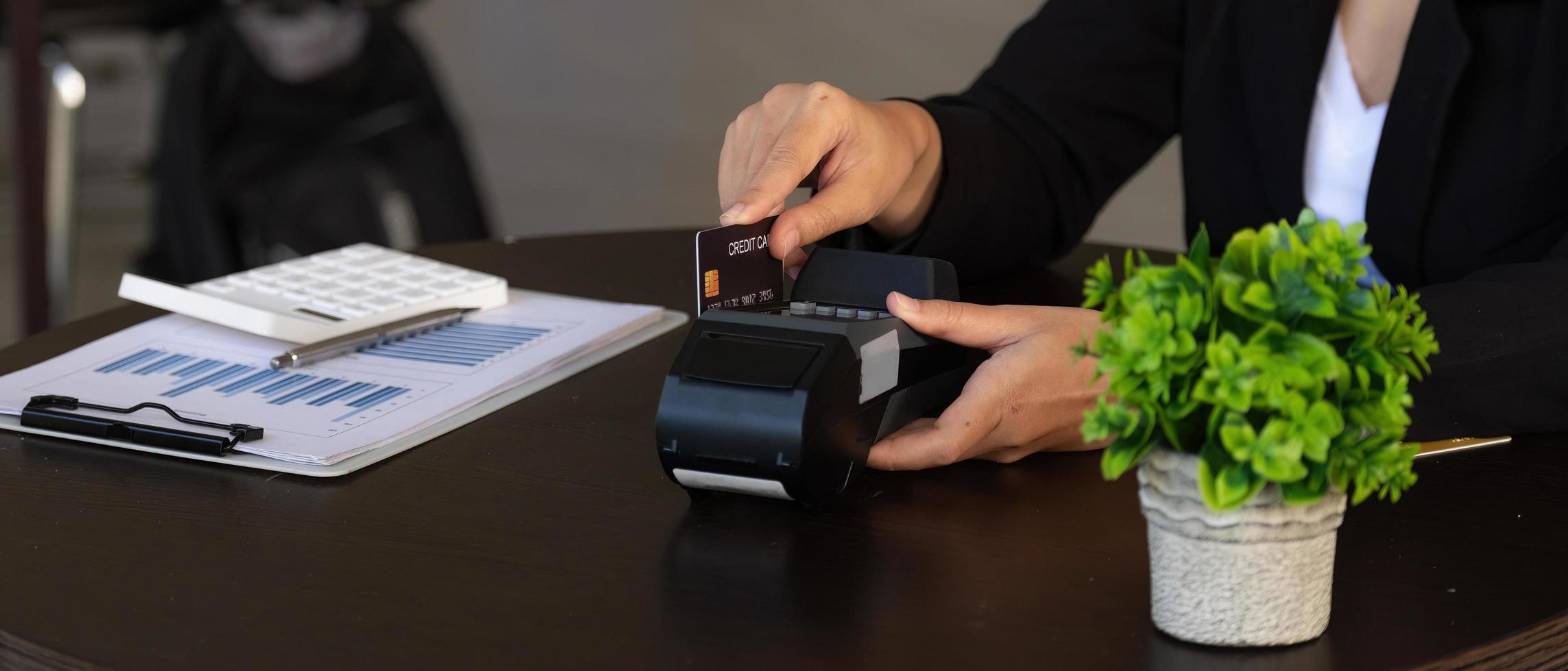 businesswoman hand pushing the button and swipe credit on terminal standing in shopping mall. shopping and retail concept photo