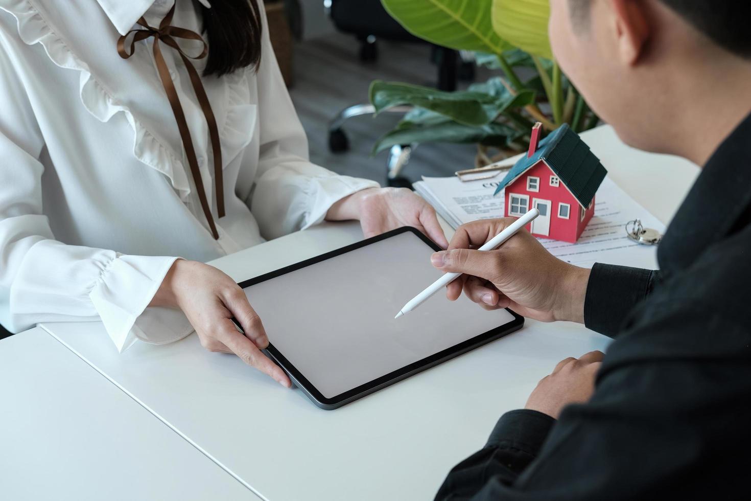 Real estate brokers point to a contract and advise customers to sign name digital tablet. customer sign agreement contract signature for buy or sell house. Real estate concept contact photo
