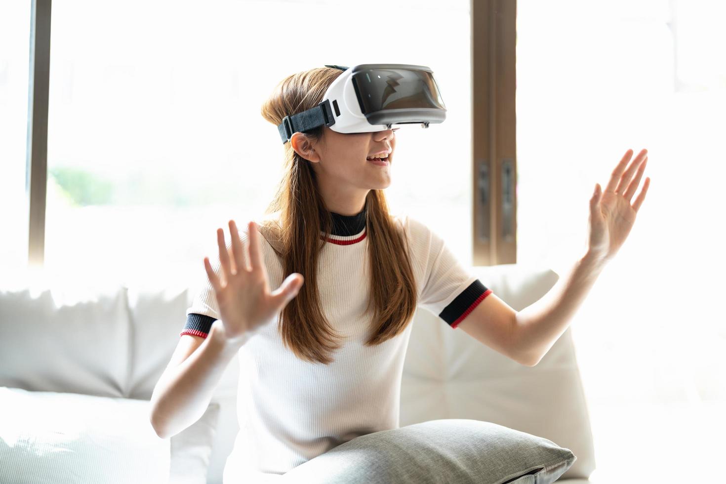 excitar a una mujer asiática jugando juegos en línea con gafas vr y controlador en su casa foto