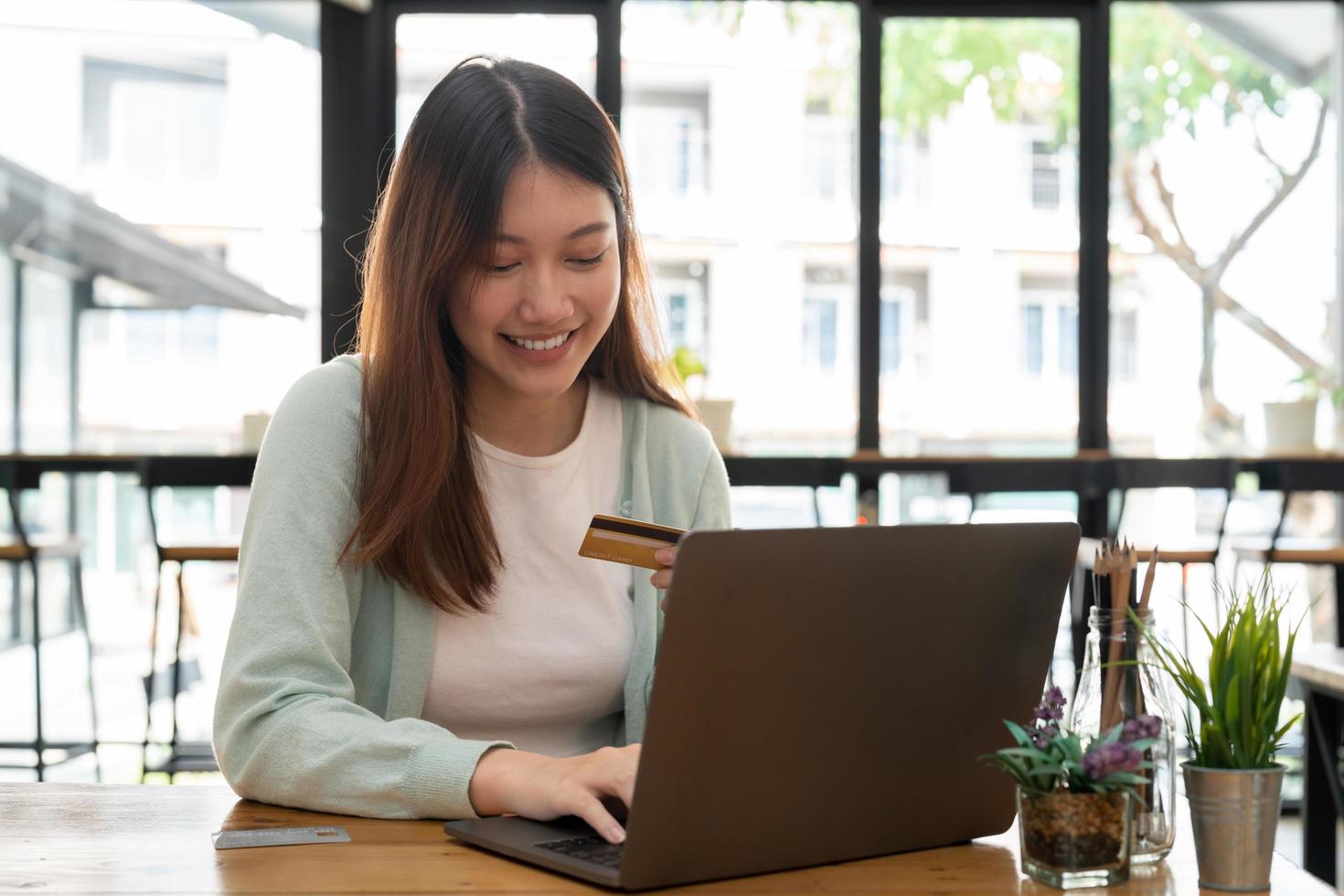 Young asian woman holding credit card and using laptop computer. Online shopping concept photo