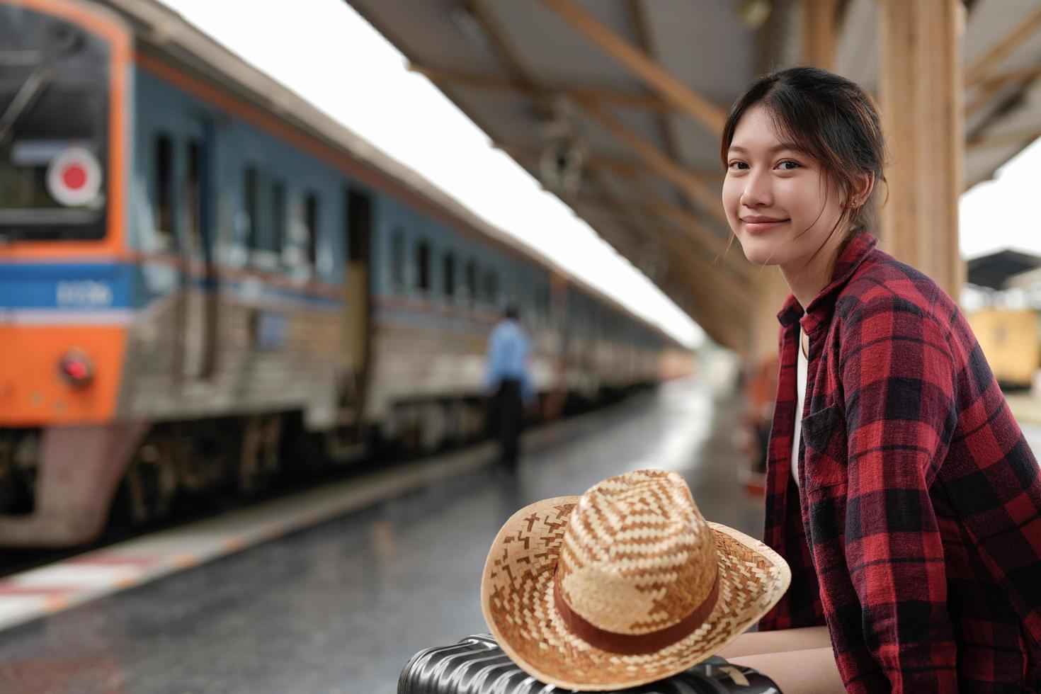 young asian woman traveler backpack waiting railway at train station, Summer holiday and travel concept photo