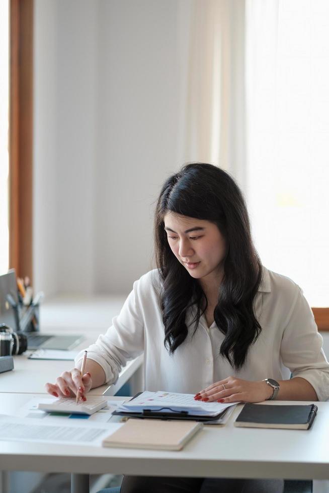 Portrait asian business woman working with calculator hand pointing graph discussion and analysis data charts and graphs.Business finances and accounting concept photo