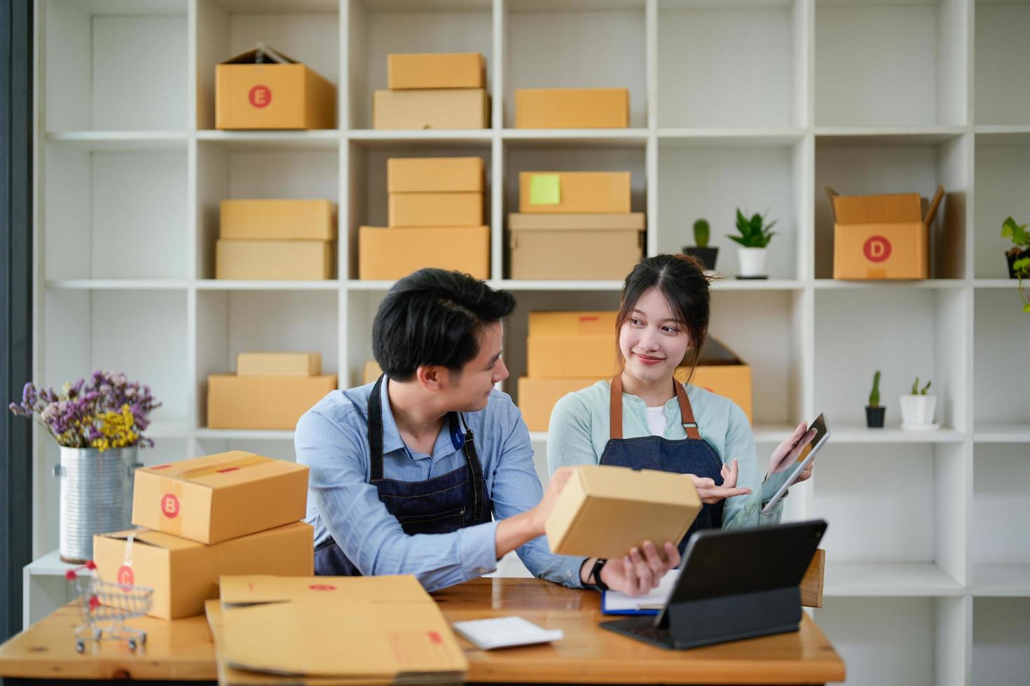 startup small business owner working with tablet at workplace. freelance man  woman seller check product order, packing goods for delivery to customer. Online selling photo