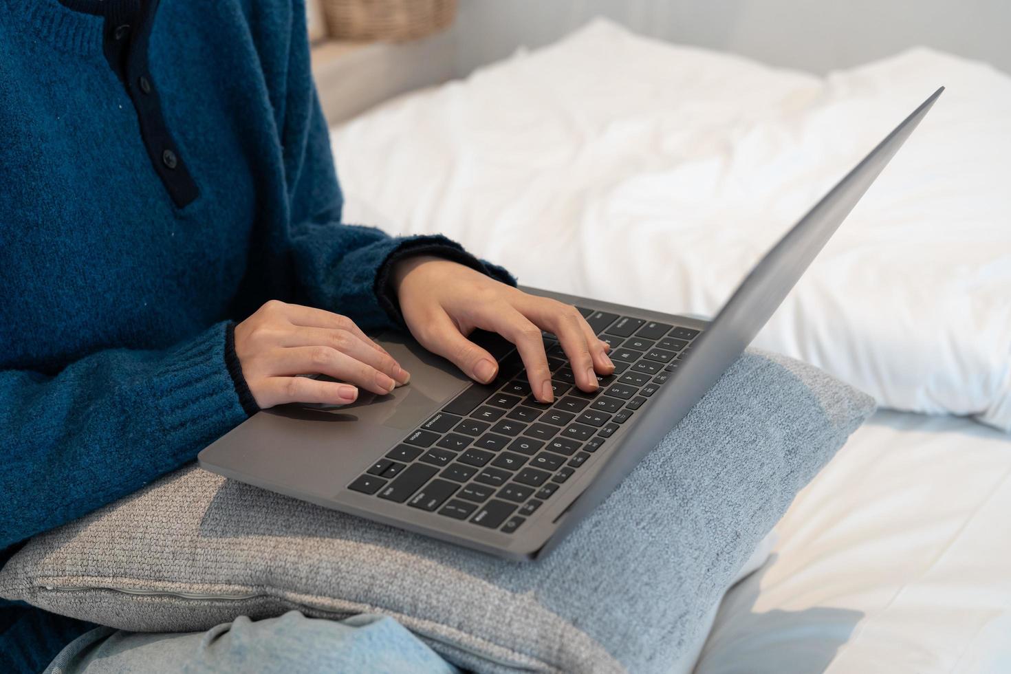 cierre las manos de una especialista que trabaja en una computadora portátil en una acogedora sala de estar mientras se sienta en una mesa. mujer independiente chateando por internet en las redes sociales. foto