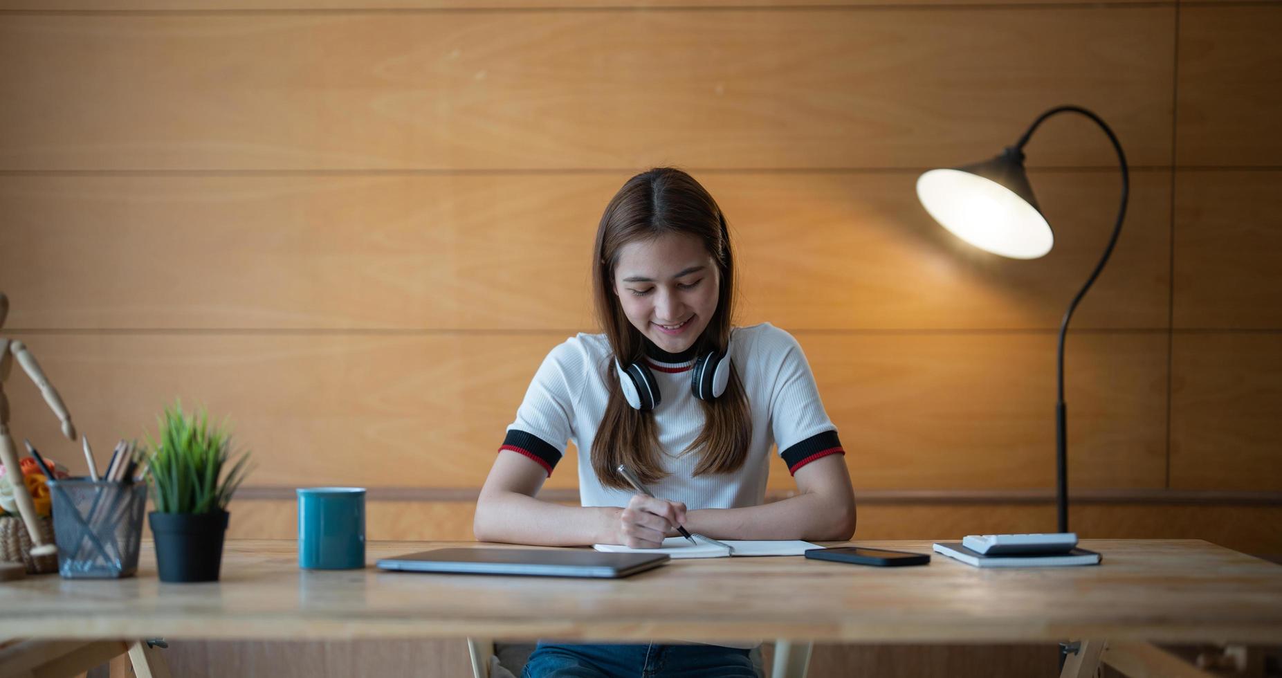 Cropped photo of woman writing making list taking notes in notepad working or learning on laptop indoors- educational course or training, seminar, education online concept.