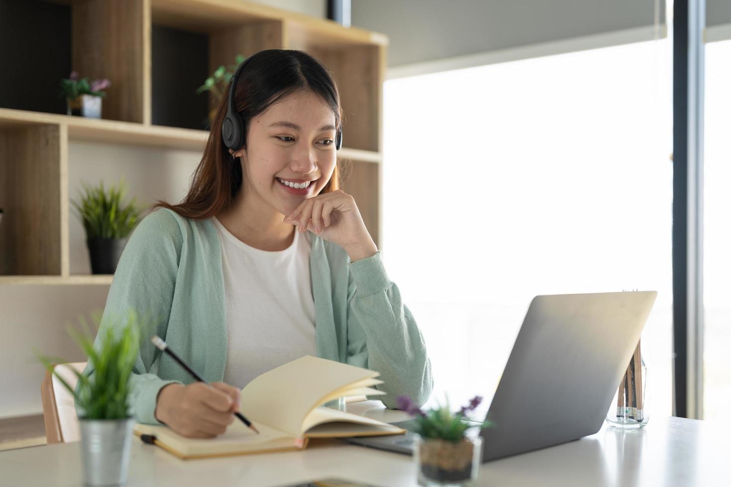 Concéntrese en un trabajador autónomo gial asiático que usa auriculares y se comunica con el cliente a través de una videollamada. tutora profesional milenaria y agradable que da clases de idiomas en línea. foto