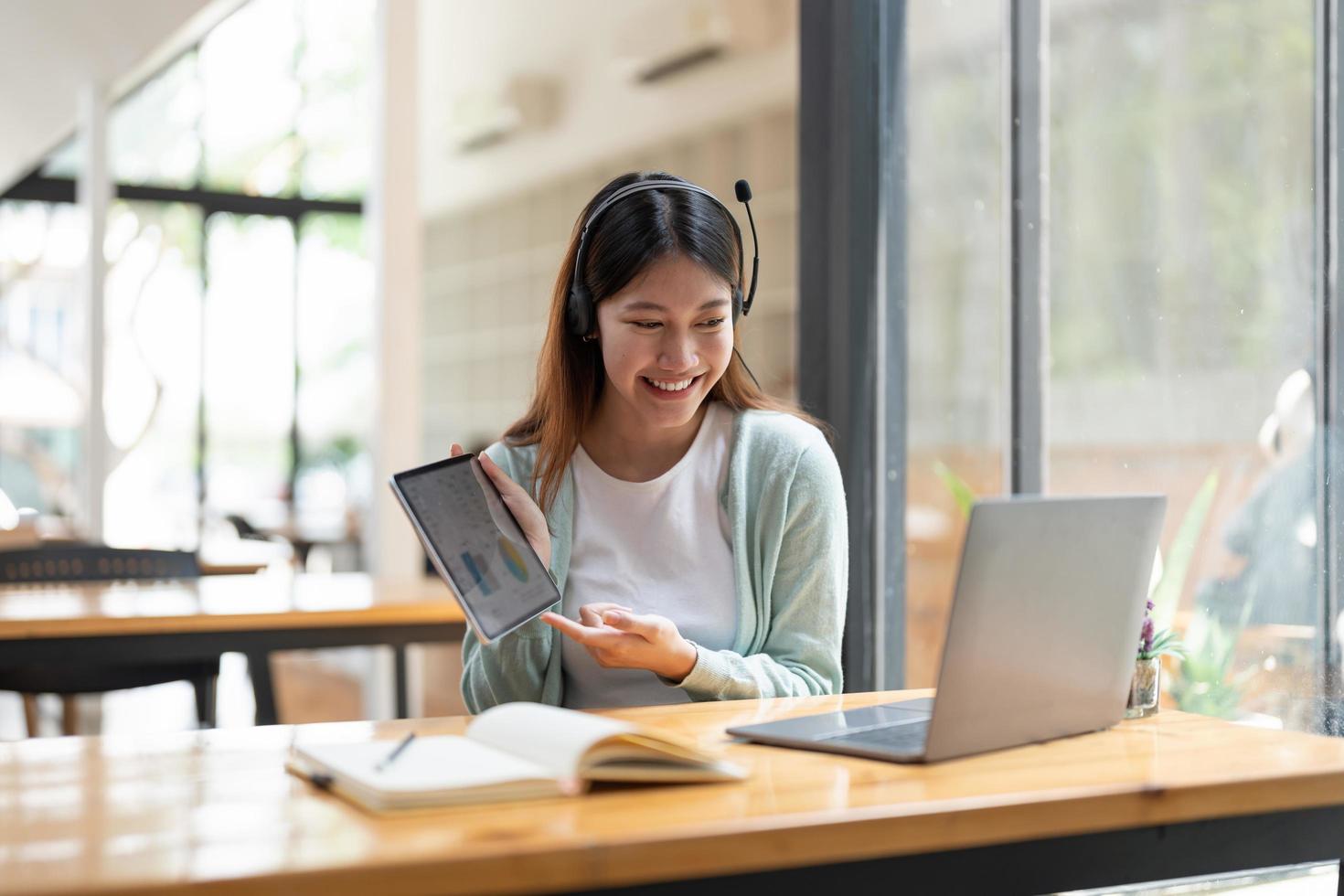 mujer asiática escribiendo haciendo una lista tomando notas en el bloc de notas y la tableta digital trabajando o aprendiendo en una computadora portátil en el interior: curso educativo o capacitación, seminario, concepto de educación en línea foto