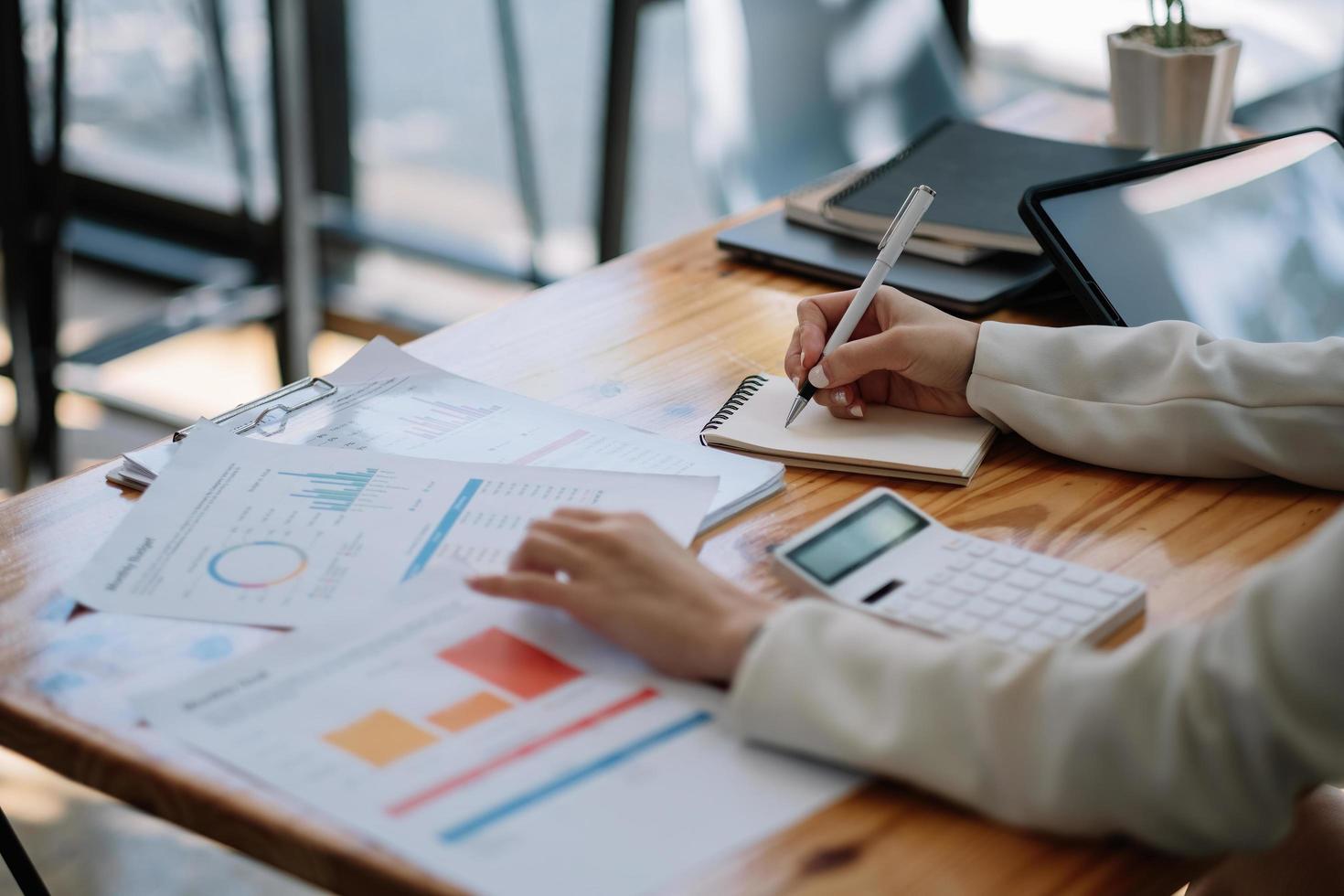 Business woman hand with charts and taking note on the notepad. Report papers and business Planning with business chart. photo