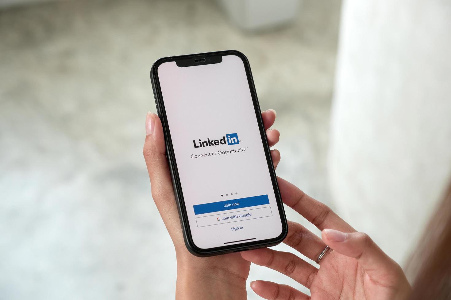 A women holds Apple iPhone 13 Pro max with LinkedIn application on the screen.LinkedIn is a photo-sharing app for smartphones photo