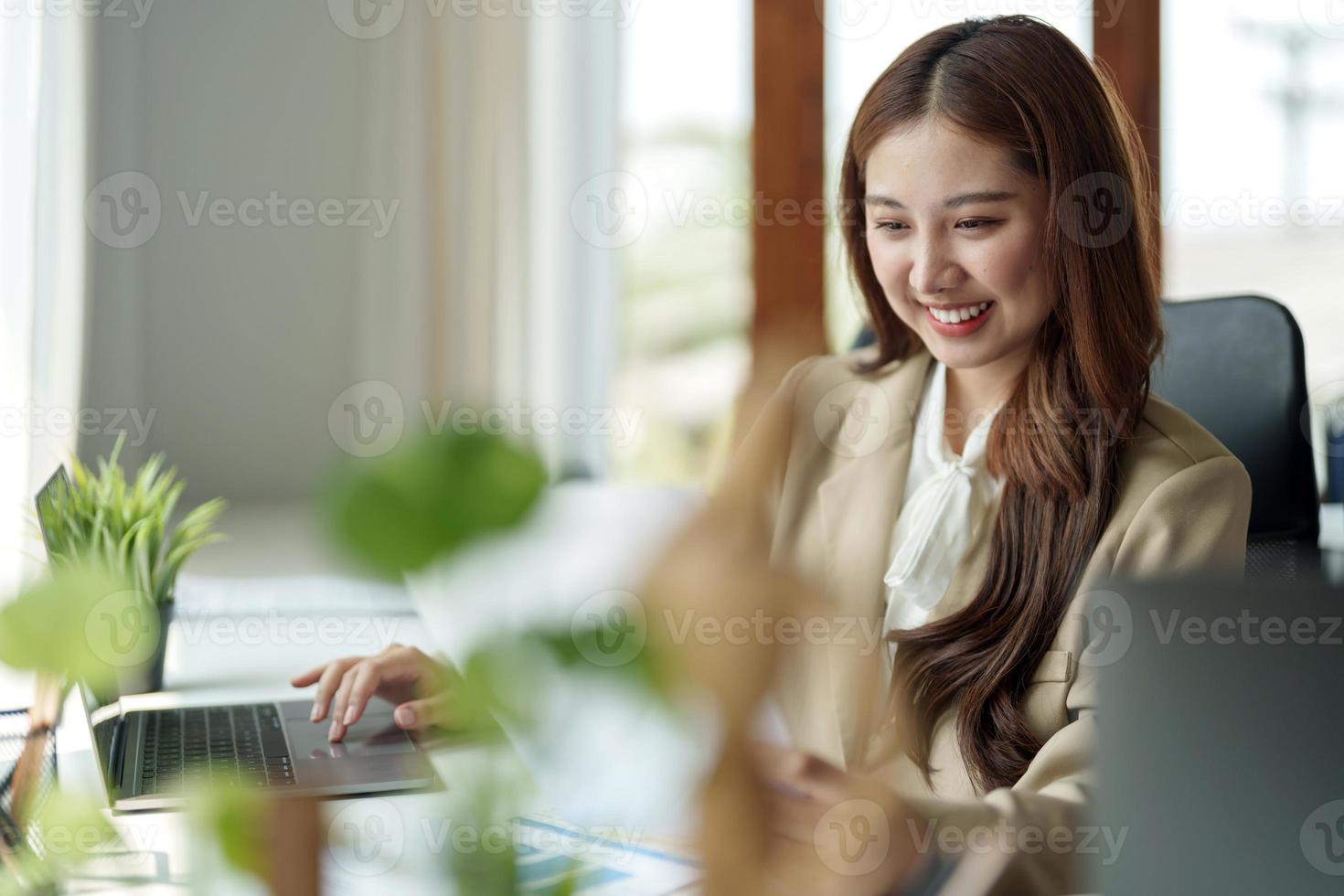 Portrait of charming young businesswoman working with laptop computer for financial on laptop in boardroom photo