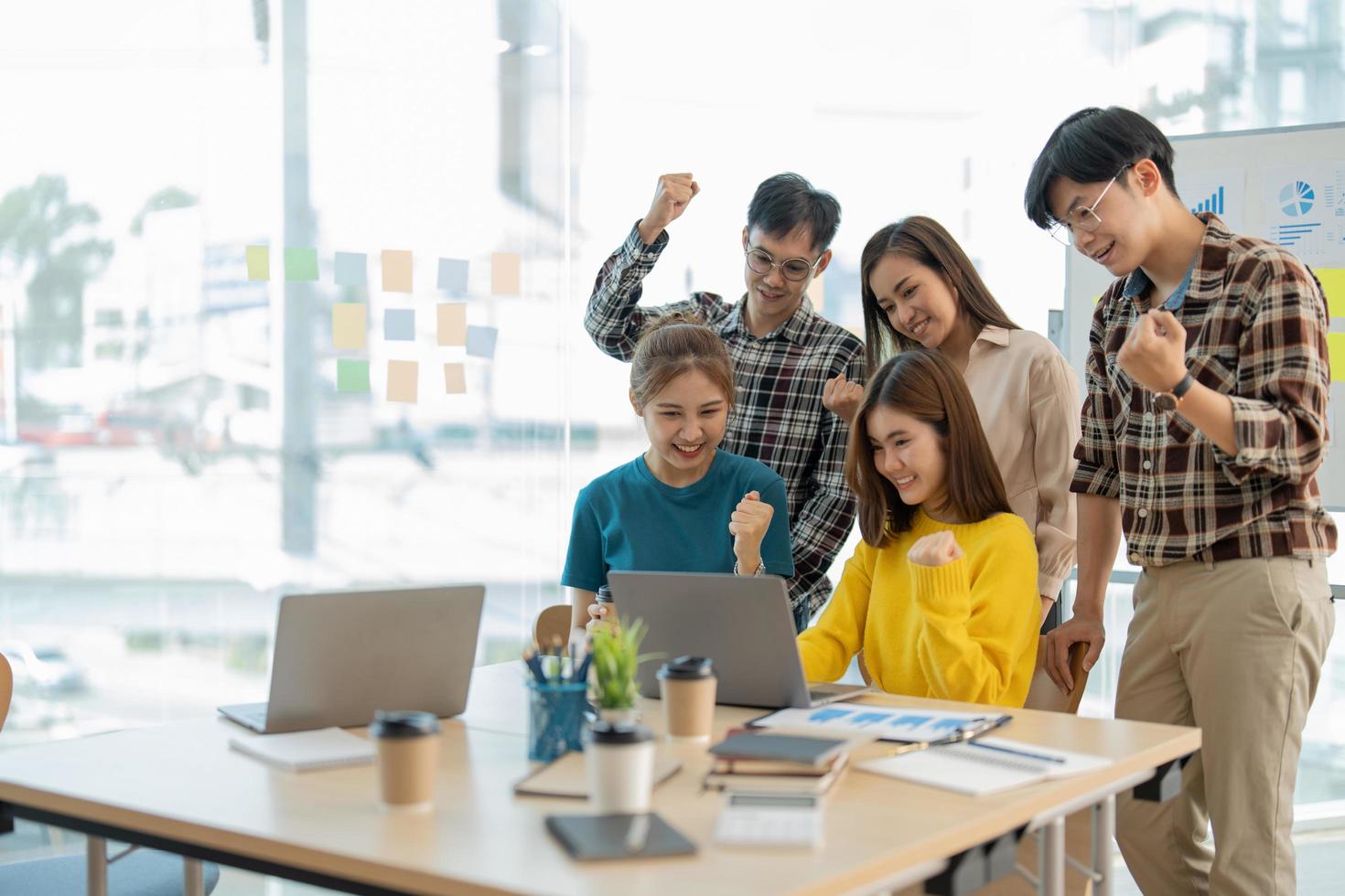 grupo de jóvenes emprendedores de equipos de negocios celebrando un triunfo con los brazos arriba, diversos empresarios feliz éxito en la sala de juntas. foto