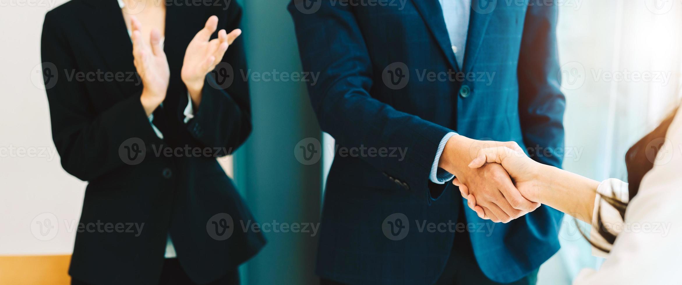 mujer de negocios aplaude y felicita mientras dos empresarios se dan la mano después de hacer un trato o acuerdo. concepto de trabajo y éxito. foto