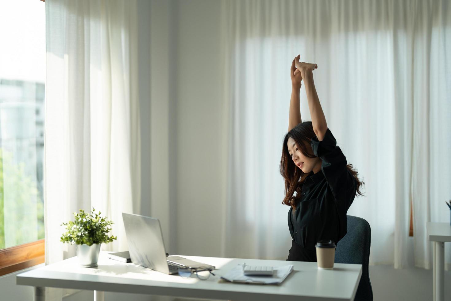 Satisfied asian woman relaxing with hands behind her head. Happy smiling employee after finish work, reading good news, break at work, girl doing simple exercise, relieve muscle stress, feeling well photo