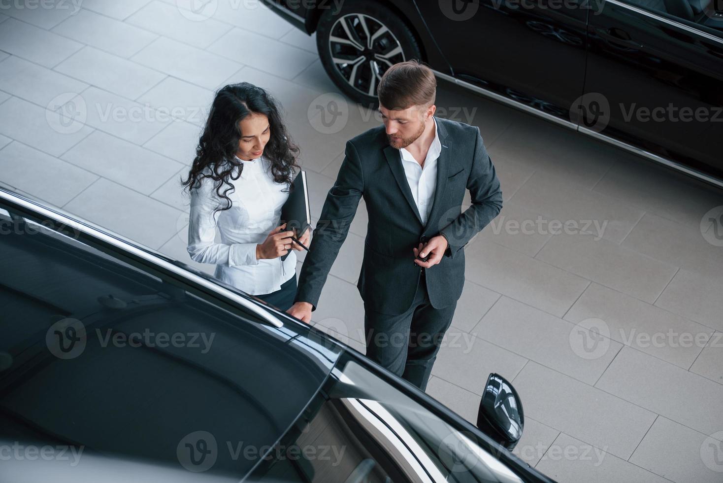 de camino al trabajo. Cliente femenino y moderno y elegante hombre de negocios barbudo en el salón del automóvil foto