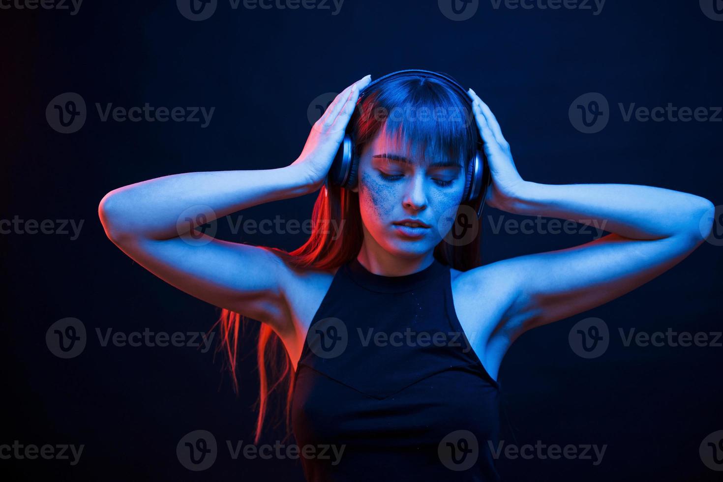 Feels good. Studio shot in dark studio with neon light. Portrait of young girl photo