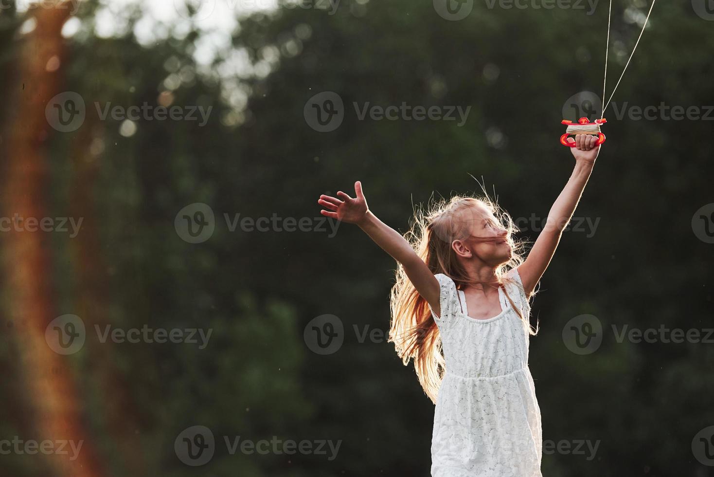 At countryside. Happy girl in white clothes have fun with kite in the field. Beautiful nature photo