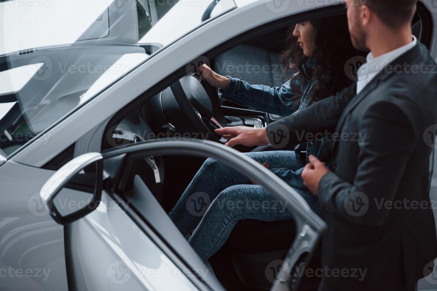 nuevo sistema de seguridad para su seguridad. Cliente femenino y moderno y elegante hombre de negocios barbudo en el salón del automóvil foto