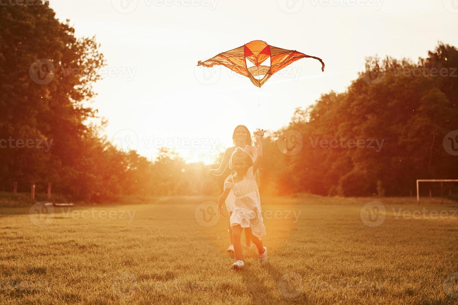 Right in the sky. Mother and daughter have fun with kite in the field. Beautiful nature photo