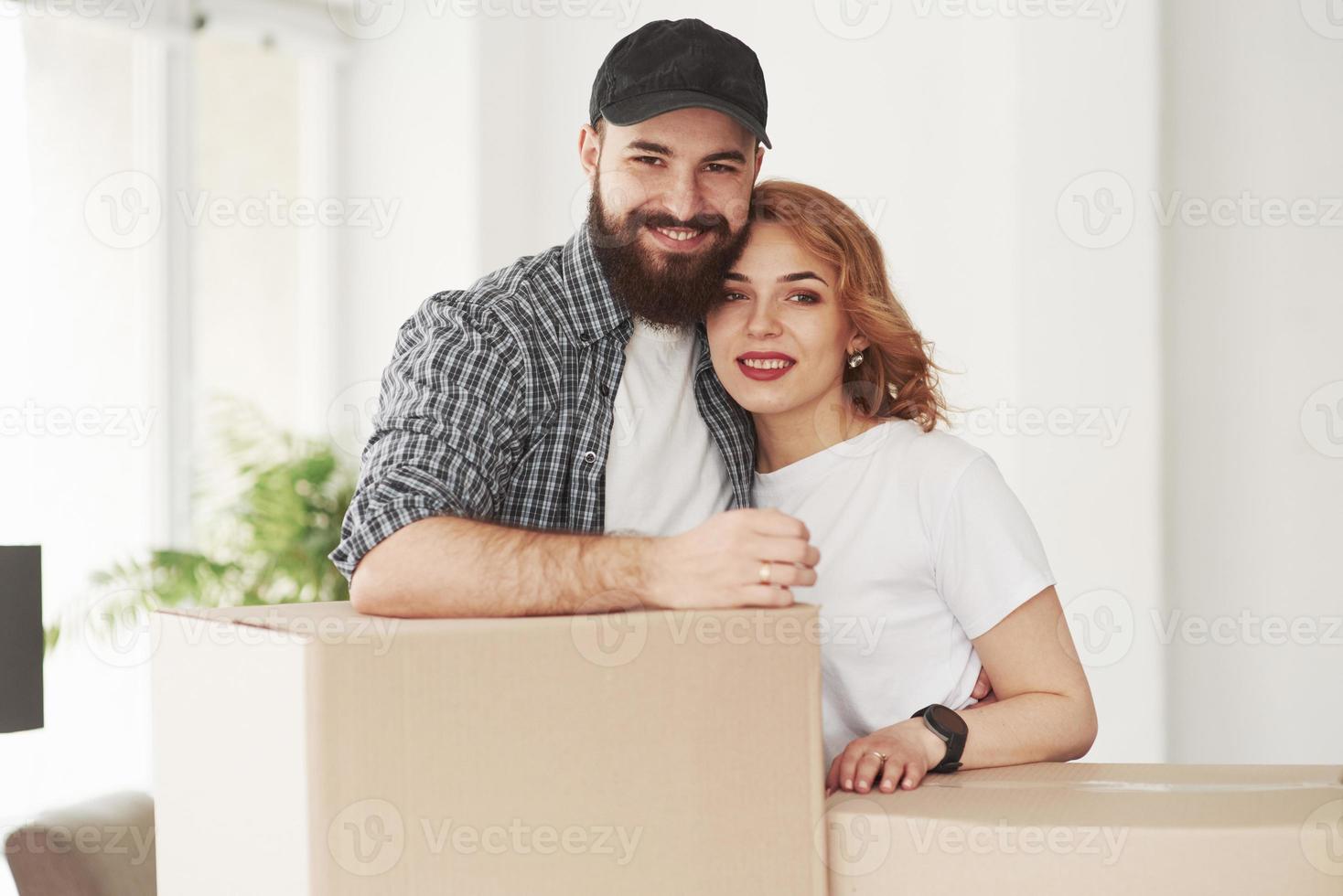 Posing for a camera. Happy couple together in their new house. Conception of moving photo