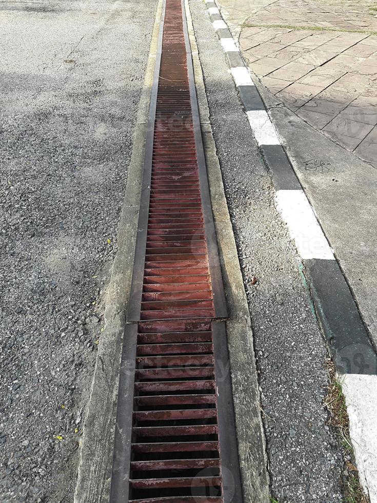 water drain or ditch on the road. Gutters drain grate, drain cover. Road drains - sewer cover. iron grate of water drain on the road in every city. Water go down to the drain on the road photo