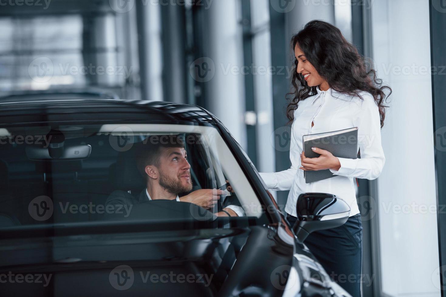 It's yours now. Male customer and modern businesswoman in the automobile saloon photo