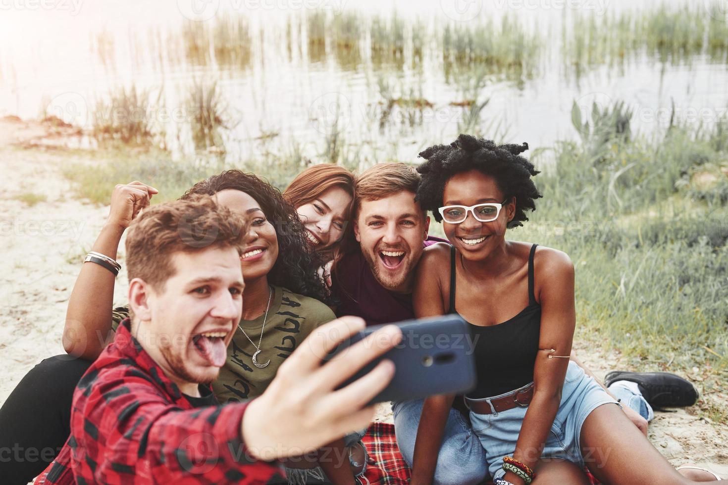 haciendo foto. grupo de personas hacen picnic en la playa. los amigos se divierten el fin de semana foto