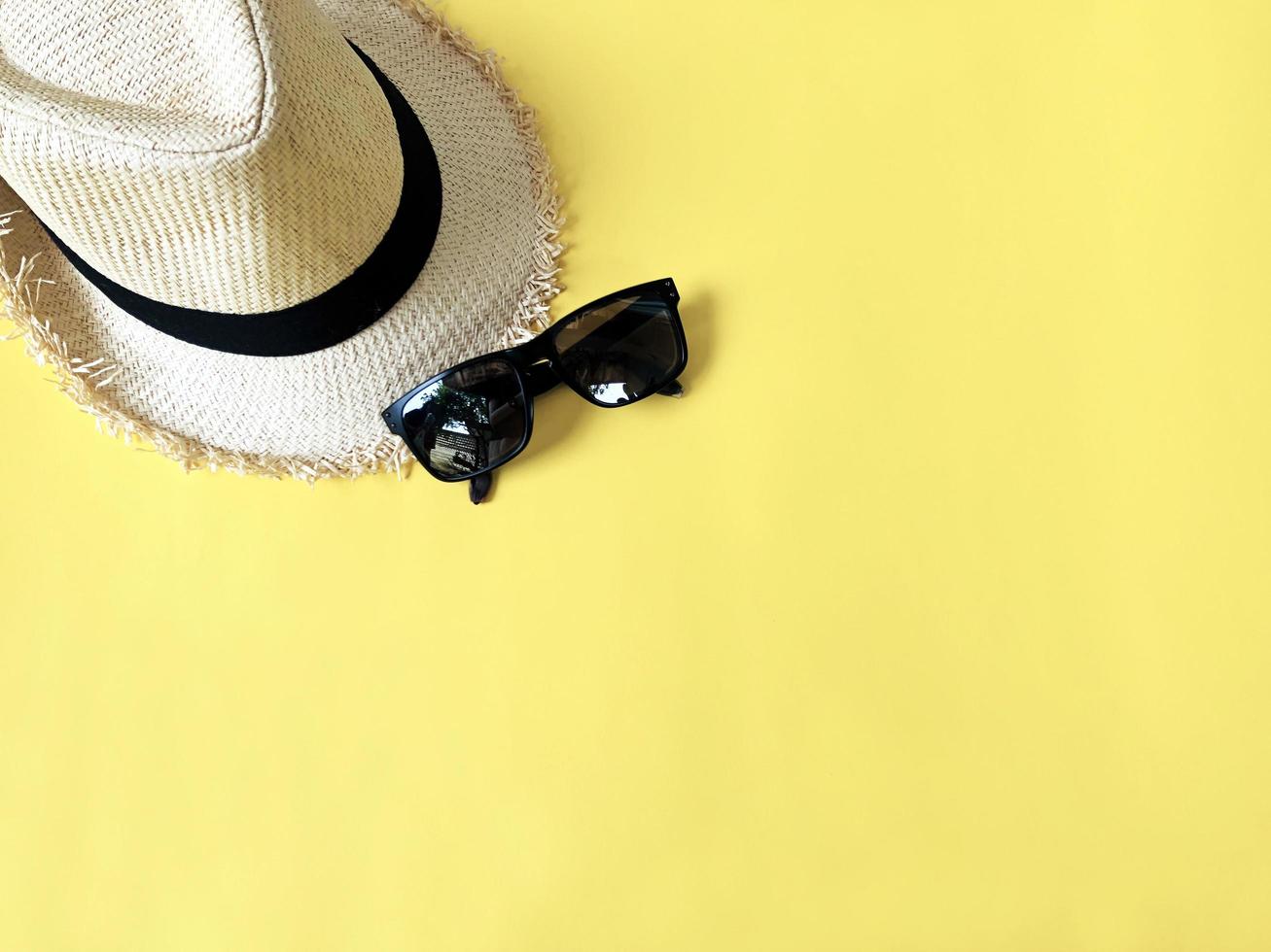 Woven hat and sunglasses on pastel yellow color background summer photo