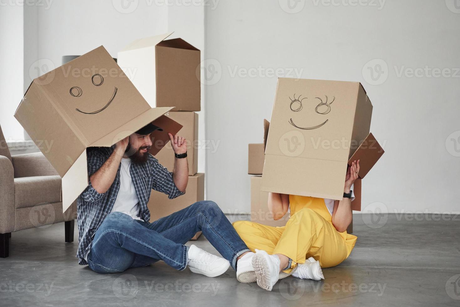 Boxes with smiley faces on it. Happy couple together in their new house. Conception of moving photo