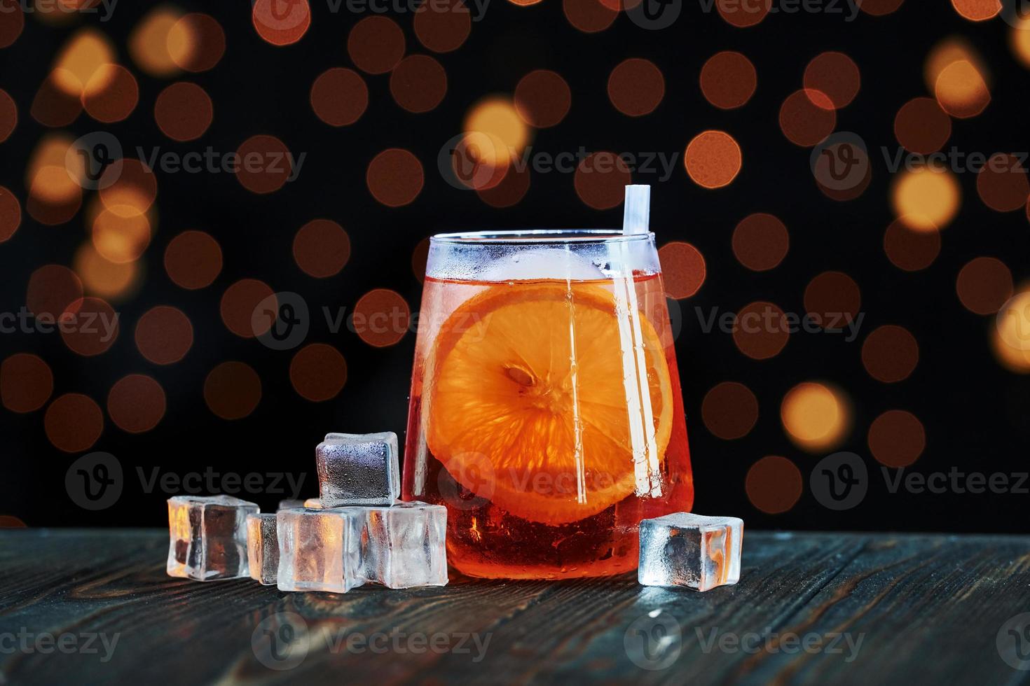 Sweet orange inside of glass. Cocktail is ready. On the wooden table in the night club. Nice lighting photo