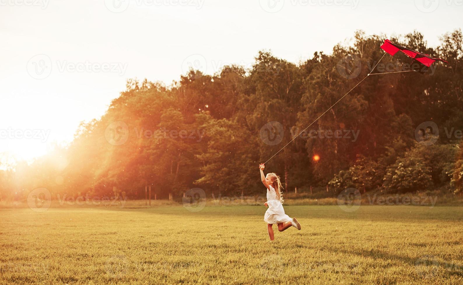 ese prado es grande. chica feliz vestida de blanco diviértete con cometa en el campo. Hermosa naturaleza foto
