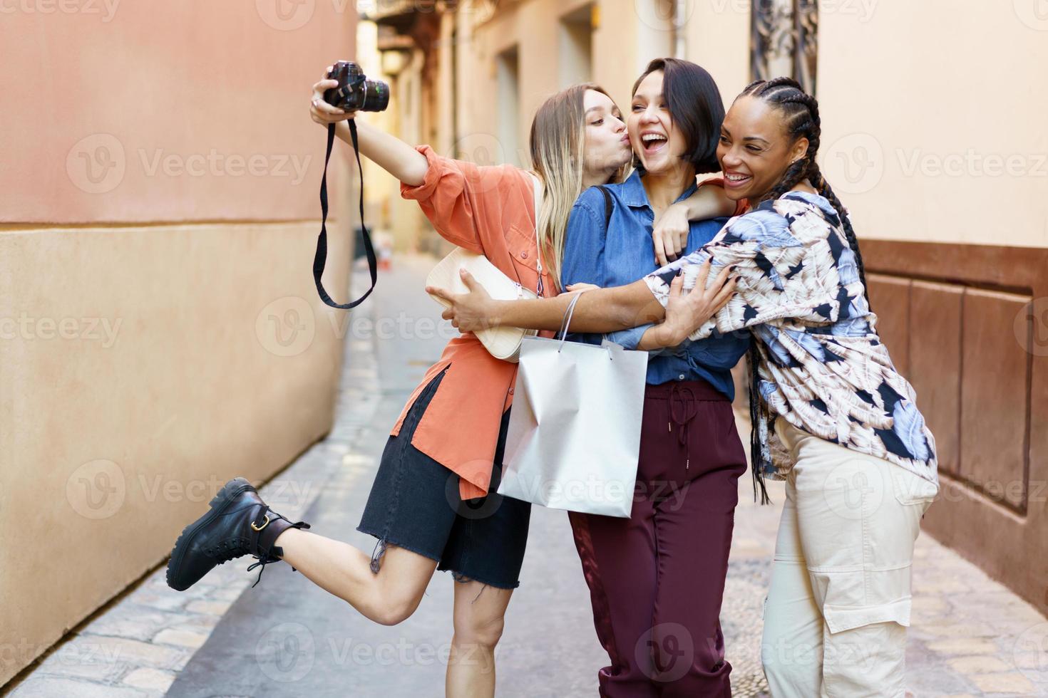 felices y diversas amigas tomando selfie en cámara en la calle foto