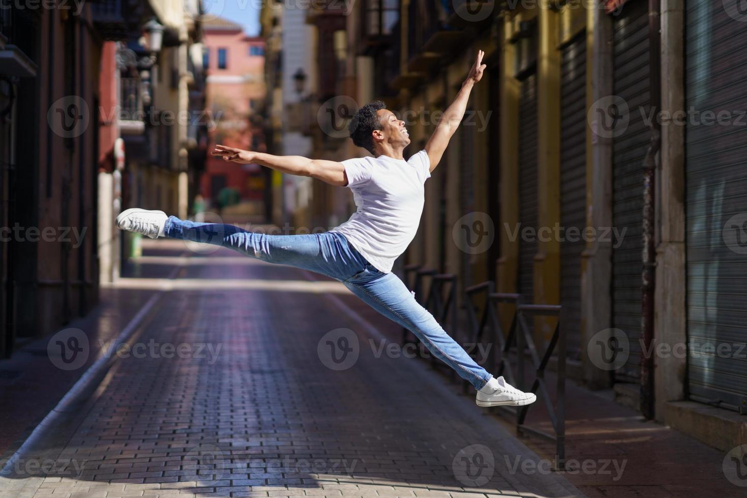 Black athletic man doing an acrobatic jump outdoors photo