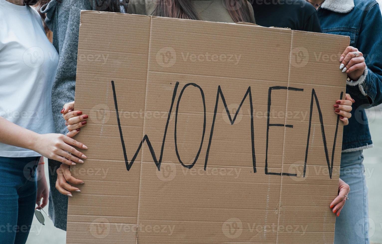 sosteniendo un gran cartel. grupo de mujeres feministas tienen protesta por sus derechos al aire libre foto
