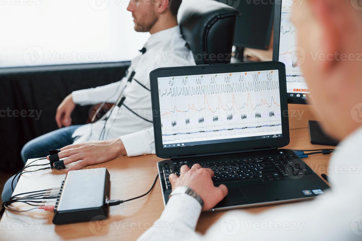 Did you saw when your neighbor is leave his house. Suspicious man passes lie detector in the office. Asking questions. Polygraph test photo