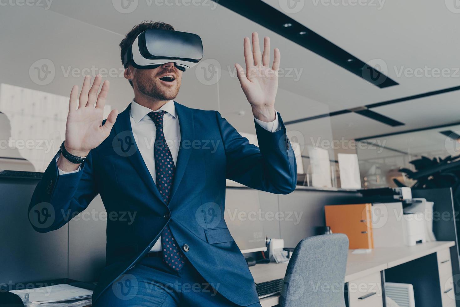 CEO man in VR headset interacting with virtual objects or interface while sitting in office photo