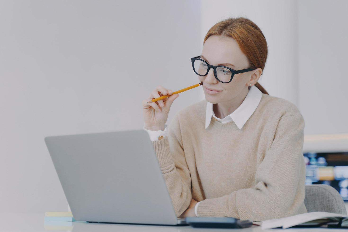 Happy attractive european girl is studying in front of laptop. Remote lesson concept. photo