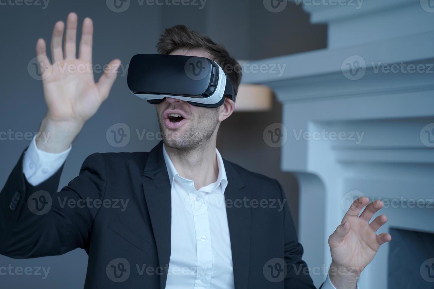 Man entrepreneur in formal suit sitting at home office while testing VR goggles photo