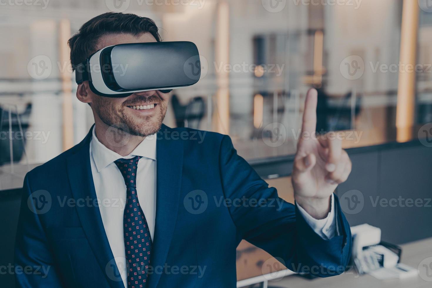 Smiling young finacier in formal suit enjoying spending time in virtual reality with VR headset photo