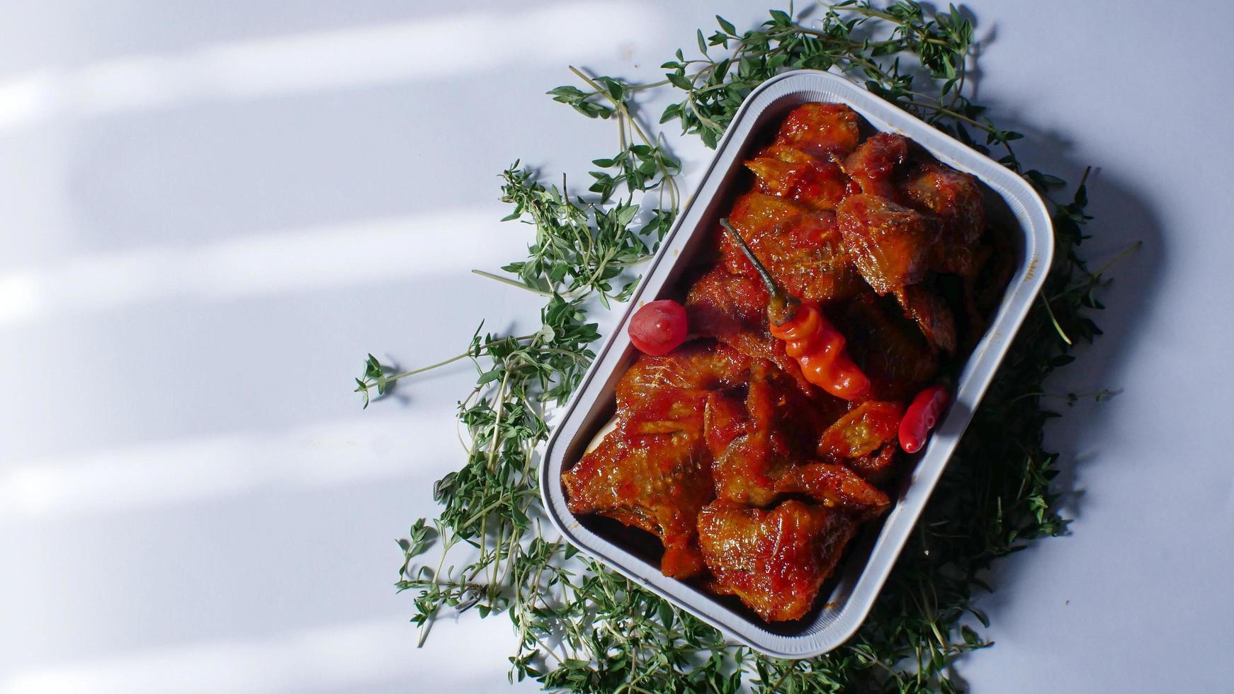 salted fish with spicy sweet and sour seasoning Indonesian food served simply in an aluminum place with white background photo