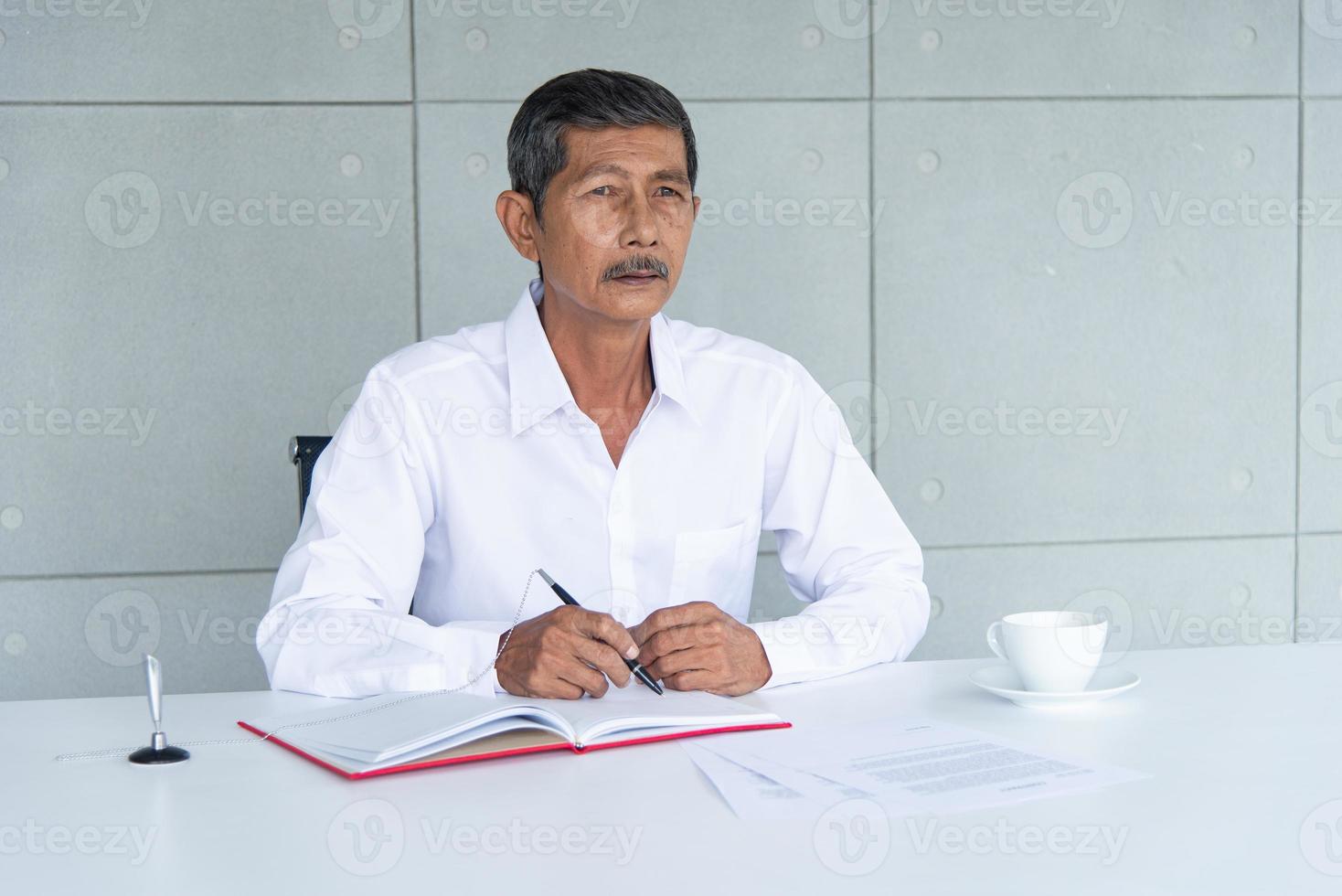 Work from home and social distancing concept. Asian business old man  working at co-working space or meeting room. Aging man sign signature. photo