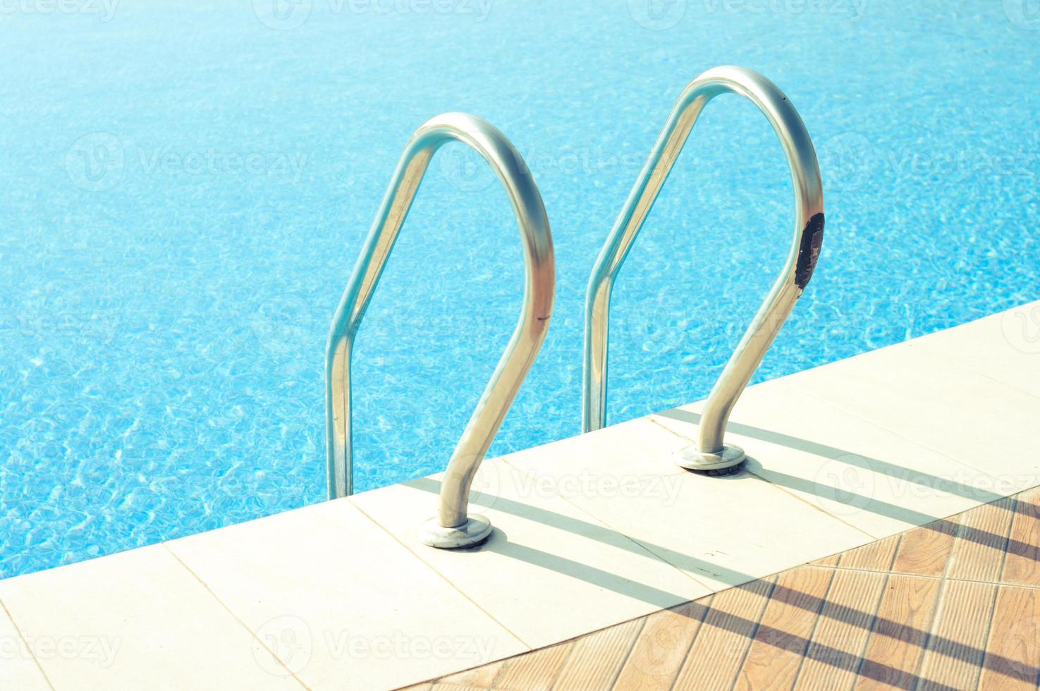 Beautiful swimming pool with shiny handrails under the bright sunlight. photo