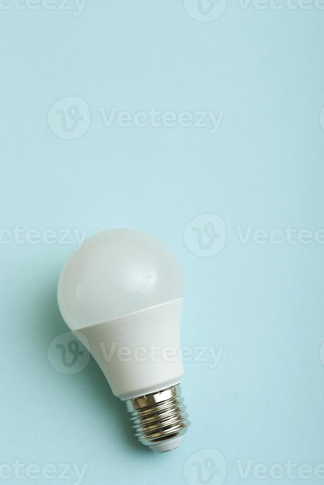 White economy light bulb on blue background with free copy paste space for text. photo