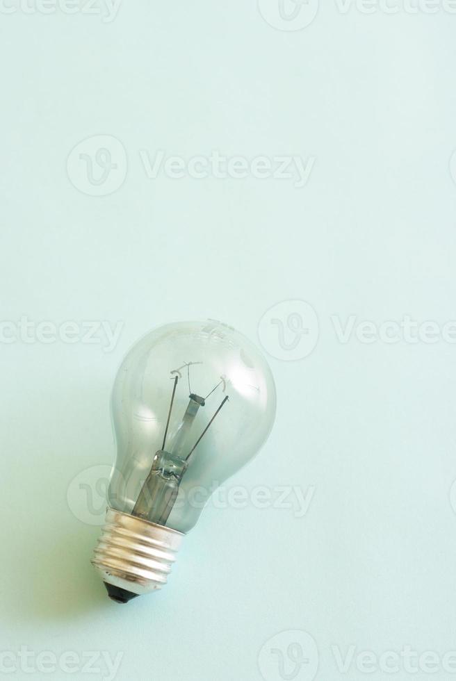 Traditional style glass light bulb with burnt tungsten on blue background. photo