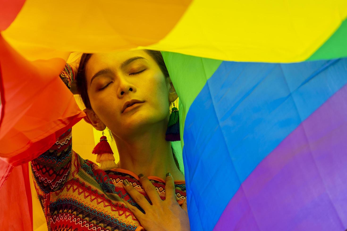 Elegance transgender model woman in colorful rainbow flag costume is dancing in homosexual parade for LGBTQ pride month and coming out of the closet concept for sexual equality and freedom concept photo