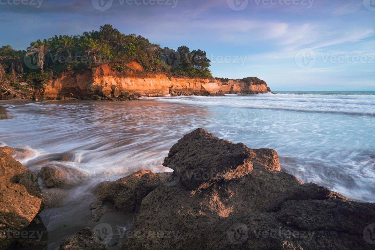 evening beach view with rocks and waves brushing the sand photo