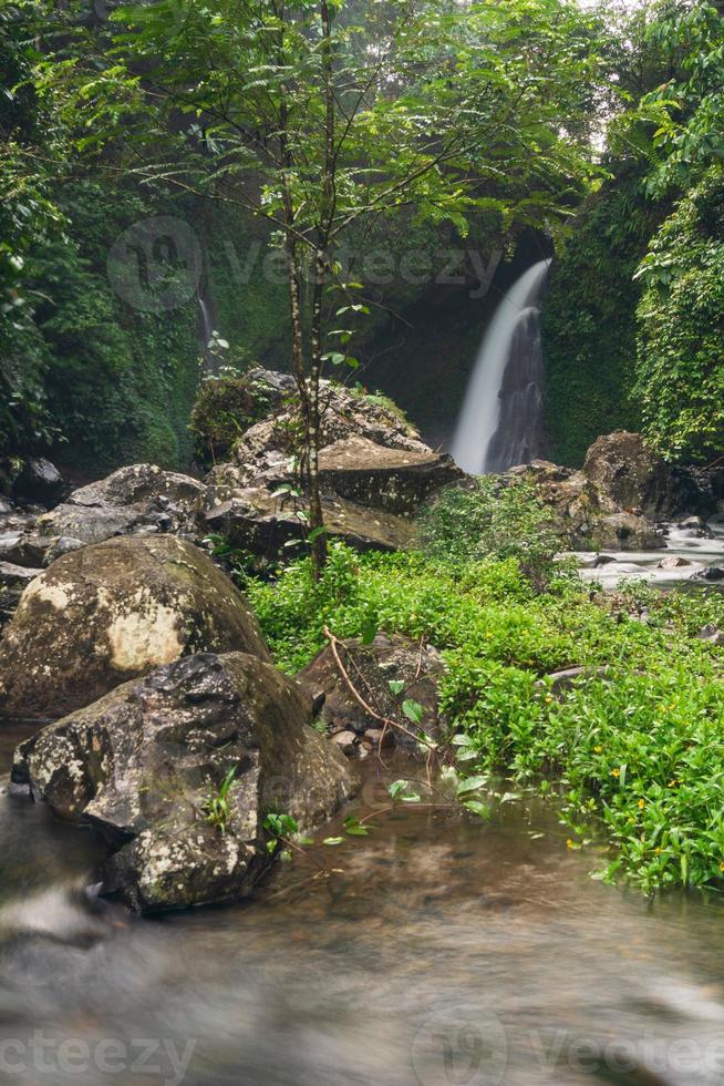 waterfall in tropical forest on cold morning rainy season in indonesia photo