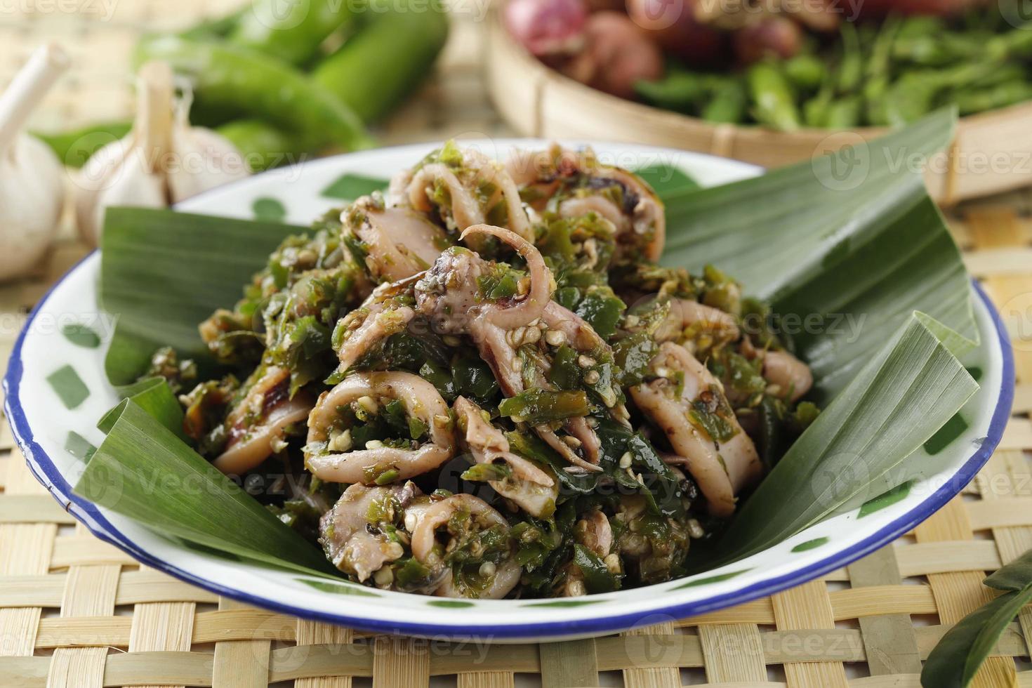 Cumi Cabe Ijo, Spicy Stir Fry Squid with Green Pepper, Shallot, and Garlic. Served on Enamel Plate on Wooden Table photo